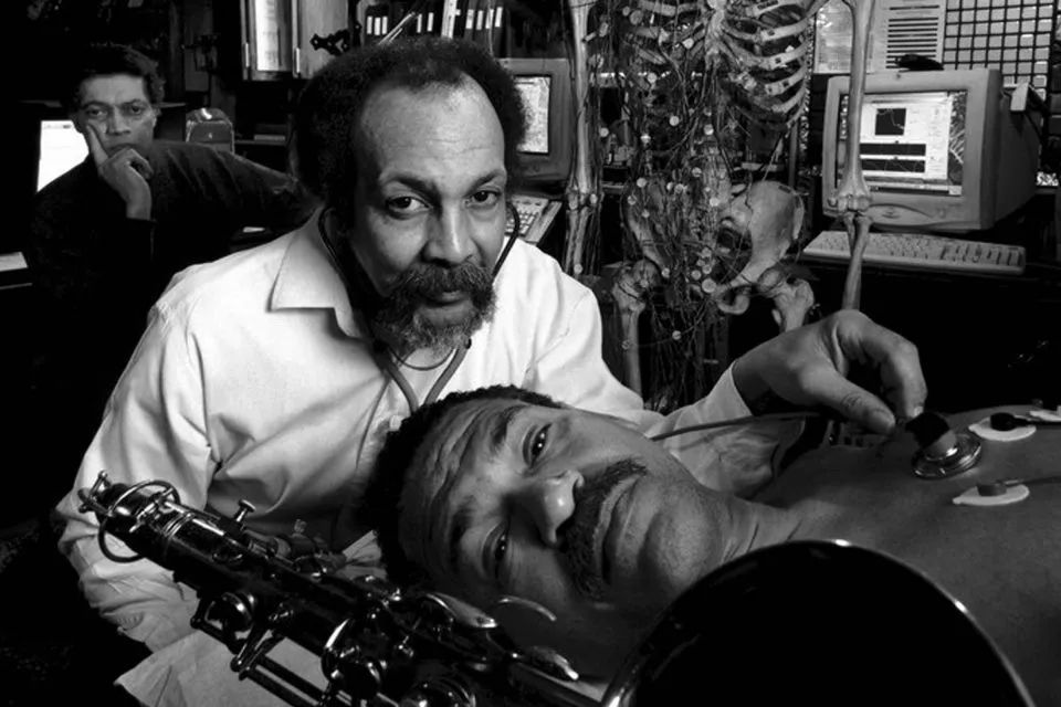 Milford Graves listens to a man heartbeat in the laboratory.