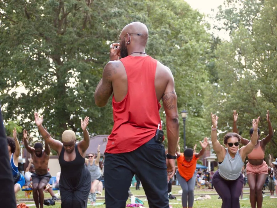 jean-jacques gabriel leads a group of yoga practitioners in a West Philadelphia park.